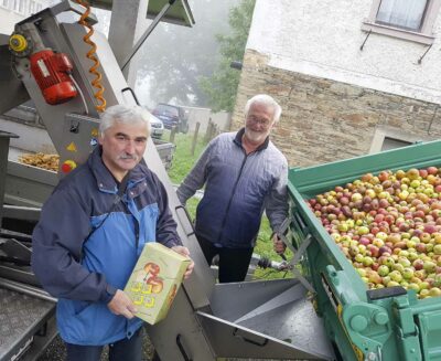 Wolfgang Petzold und Siegmar Hommel helfen, die aus der Streuobstwiese geholten Äpfel in die Saftpresse zu geben